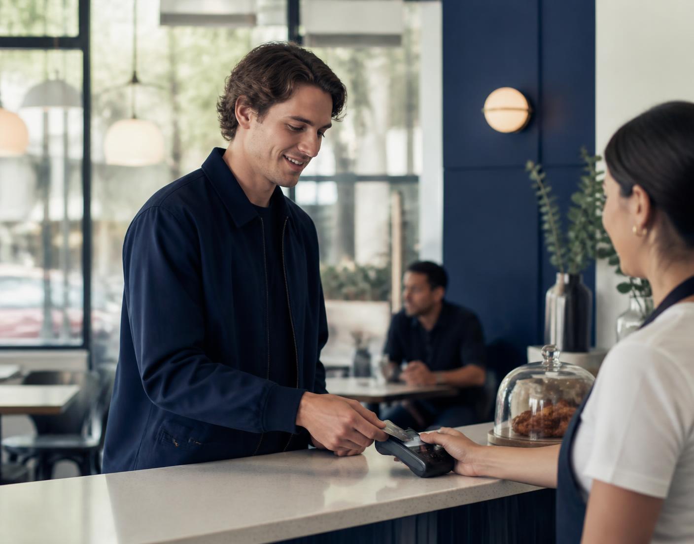 A customer paying with a Capitalix card at a cafe counter